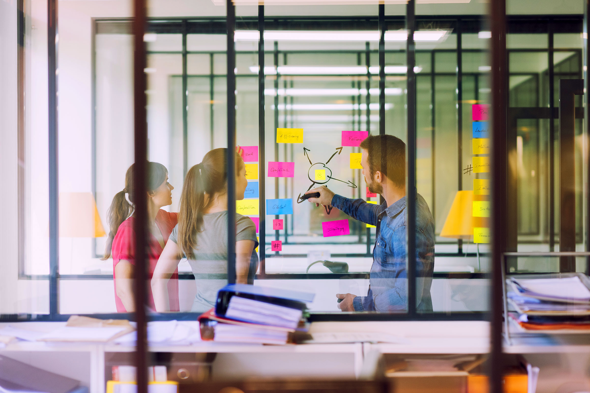 Group-of-business-people-working-in-front-of-glass-wall-with-post-notes